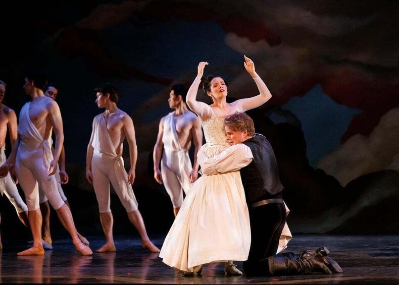 A ballet performance with dancers in white costumes on stage. 4