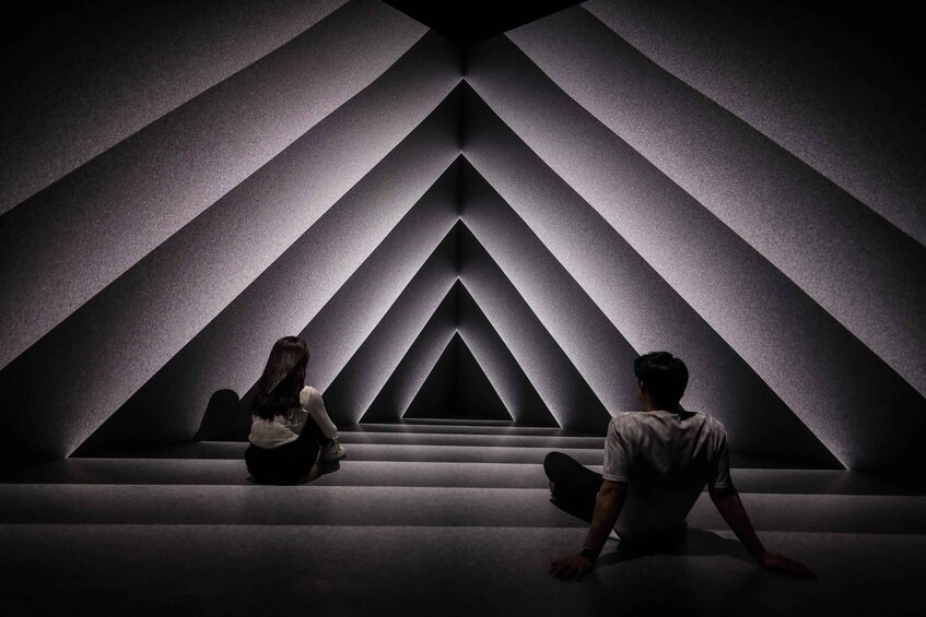 A person sitting on steps in a geometric patterned room. 4