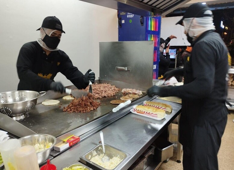 A kitchen with chefs preparing food on a grill. 1