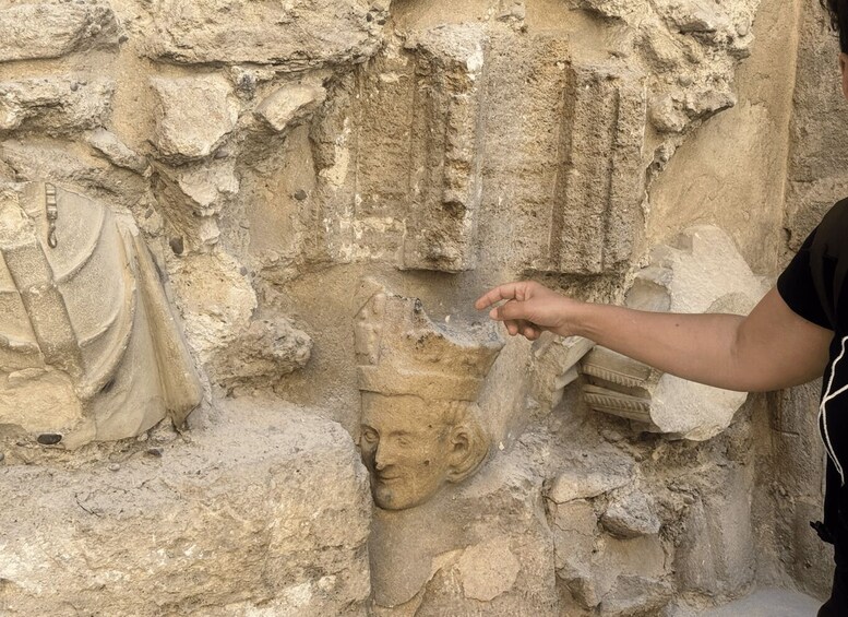 A person touching a stone relief sculpture on a weathered wall. 3