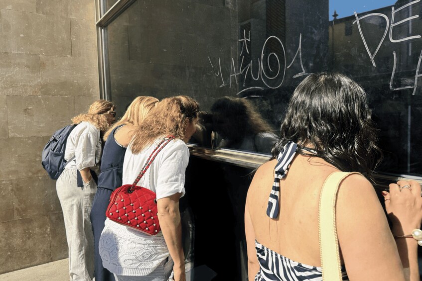 People standing at a window with graffiti on it. 4