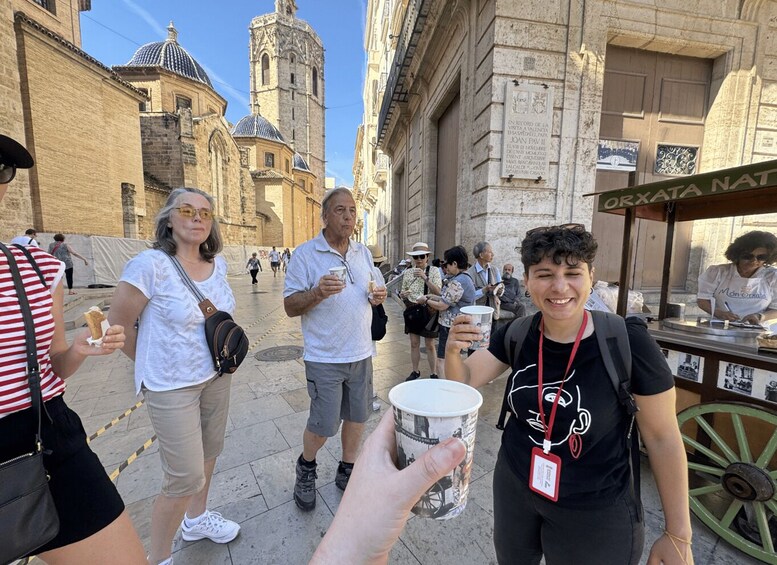 A street scene with tourists, a food cart, and historic buildings. 2
