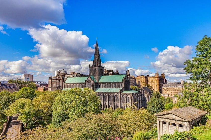 A historic cathedral with a tall spire, surrounded by lush greenery and other historic buildings. 3