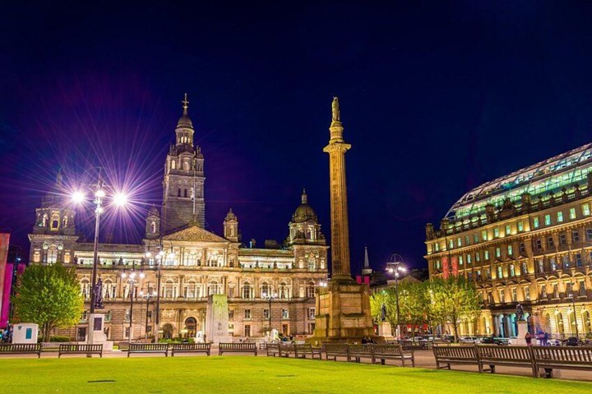 A historic building with a tall tower and a monument in the foreground. 1