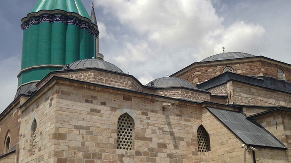 A mosque with a green dome and stone walls. 2