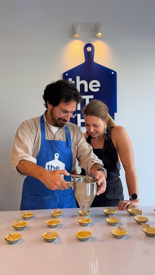 Two people preparing small pastry boats with a funnel. 5