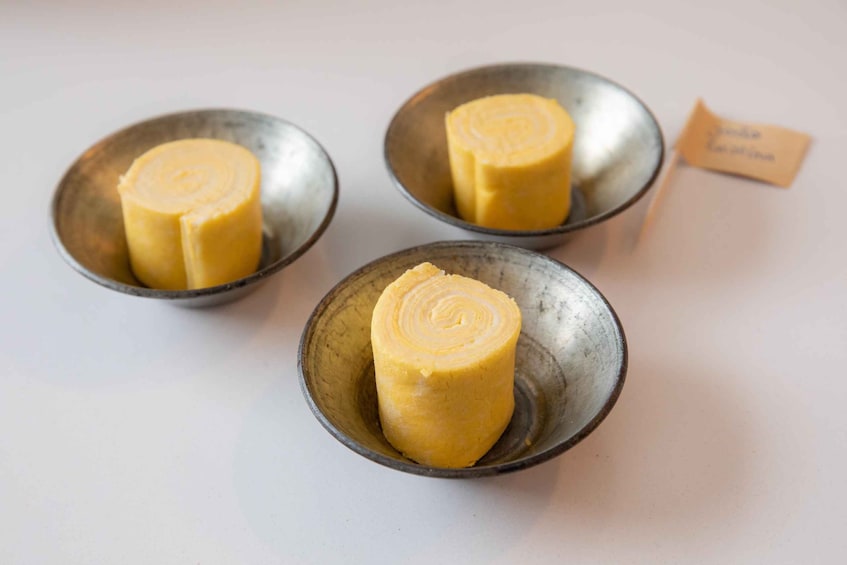 Three metal bowls containing a yellow cylindrical food item. 5