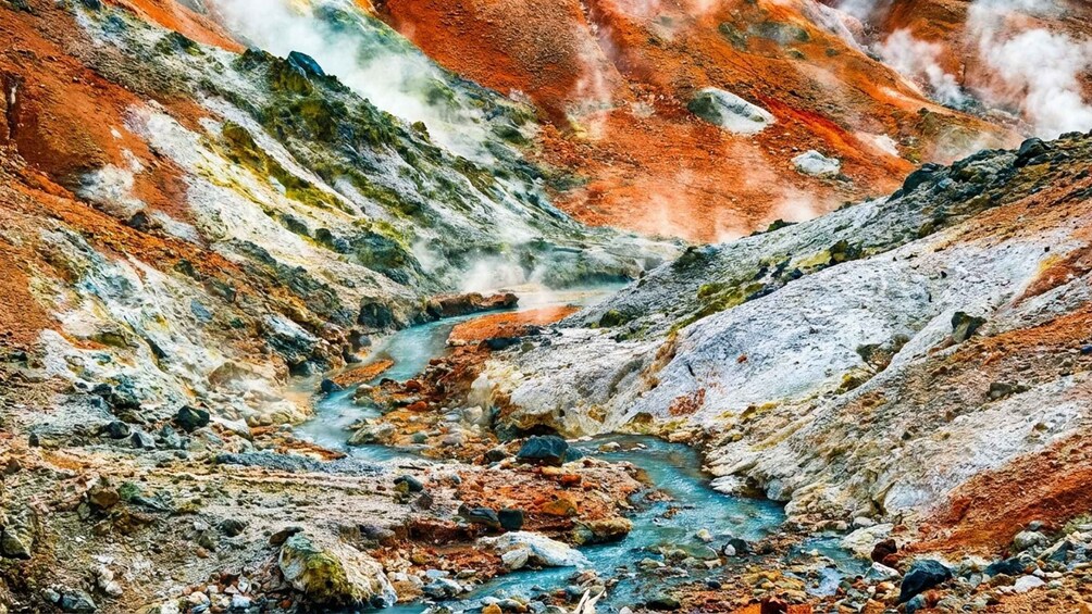 A colorful geological formation with a stream flowing through a rocky valley. 2