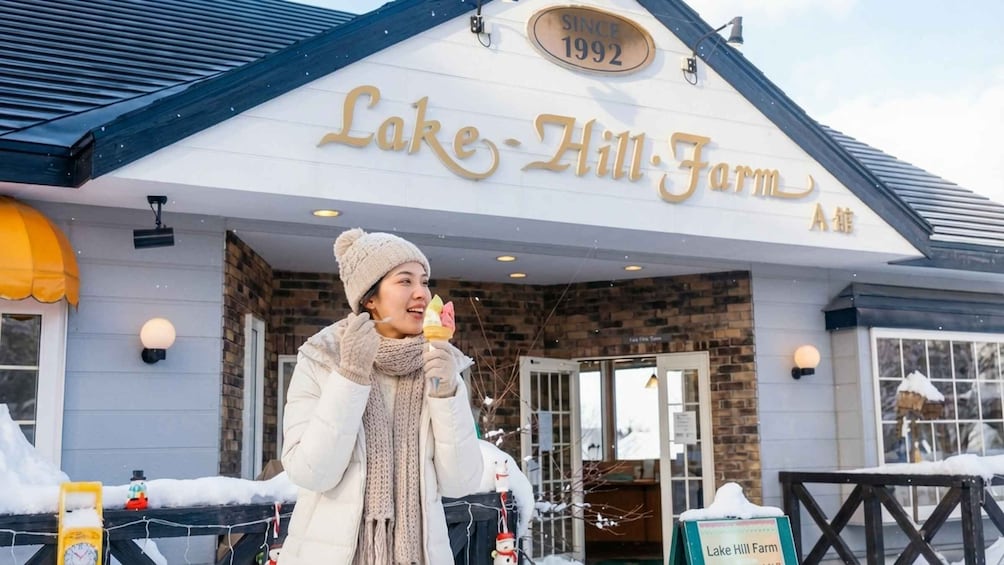 A person in winter clothing outside a building with a sign reading 'Lake Hill Farm' and 'Since 1992'. 5