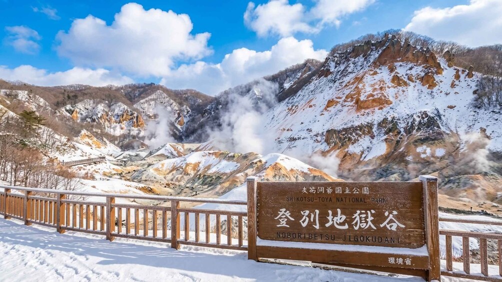 A snowy mountain landscape with a wooden sign indicating Noboribetsu Jigokudan. 4