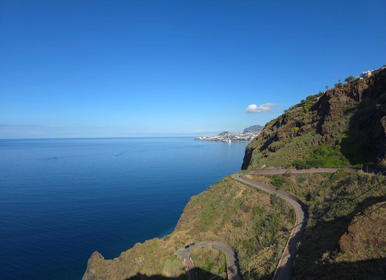 A coastal road winding along a cliffside with a view of the ocean and distant cityscape. 5