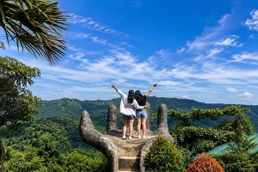 Two people embracing on a stone structure with a view of a forested landscape. 1