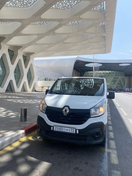A white Renault car parked in front of a modern building with geometric patterns and a curved roof. 1