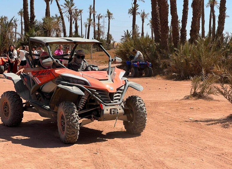 A red off-road vehicle with passengers, parked on a dirt road surrounded by palm trees. 5
