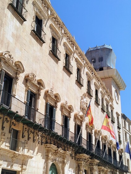 A historic building with ornate architectural details, including columns, balconies, and flags. 4