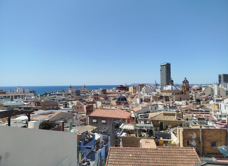A coastal cityscape with a mix of historic and modern buildings, a prominent tower, and a clear view of the sea. 2