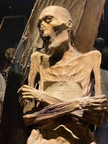 A skeletal figure with a cloth draped over its shoulders, held by a wooden structure. 1