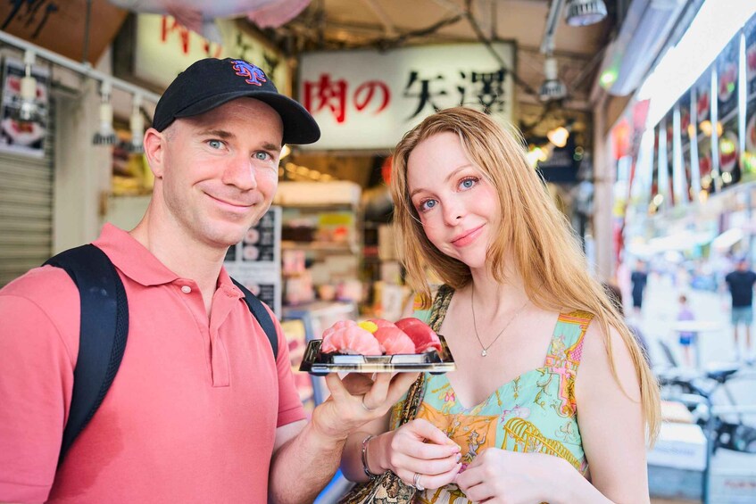 A man and a woman in a market, with the man holding a tray of food. 1
