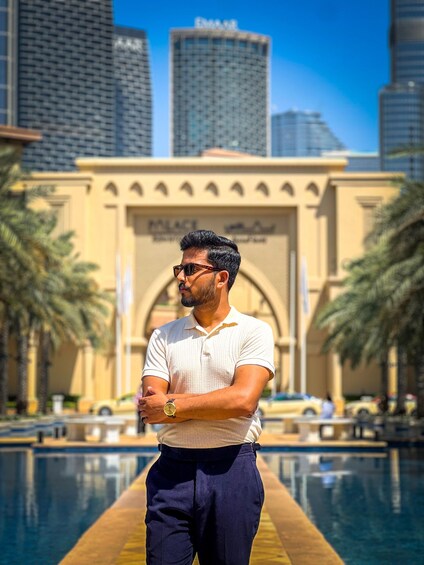 A man standing in front of a building with palm trees and a pool. 2