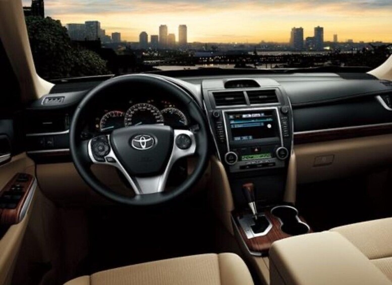 The interior of a Toyota car with a cityscape view through the windshield. 5