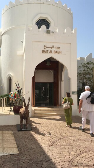 The entrance to Bait Al Bagh with a decorative camel statue and a sign in Arabic. 2