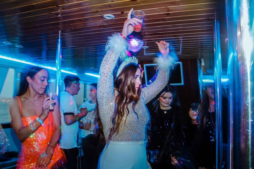 People dancing at a party with colorful lighting and reflective surfaces. 4