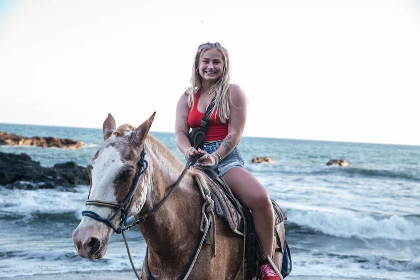 A person riding a horse on a beach with the ocean in the background. 2