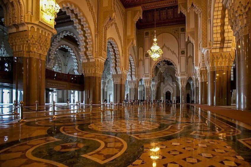 An ornate interior with high arches, intricate tile work, and a grand chandelier. 5