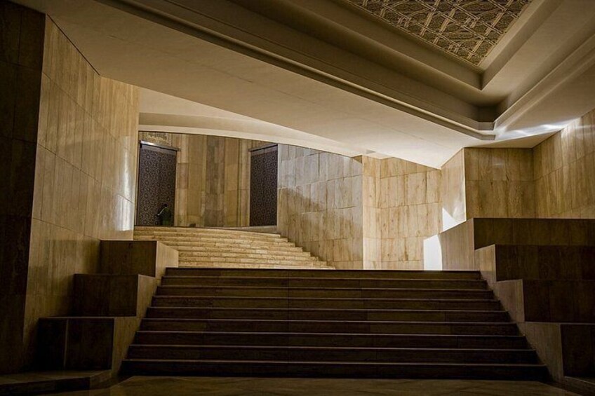 A grand staircase with marble walls and a geometric ceiling design. 3