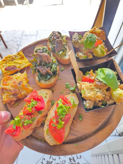 A wooden board with various food items, including bread with toppings and a small bowl of salad. 4