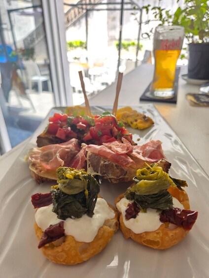A plate of appetizers including bruschetta and stuffed vegetables. 2