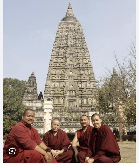 A group of monks sitting in front of a large, intricately carved temple. 3