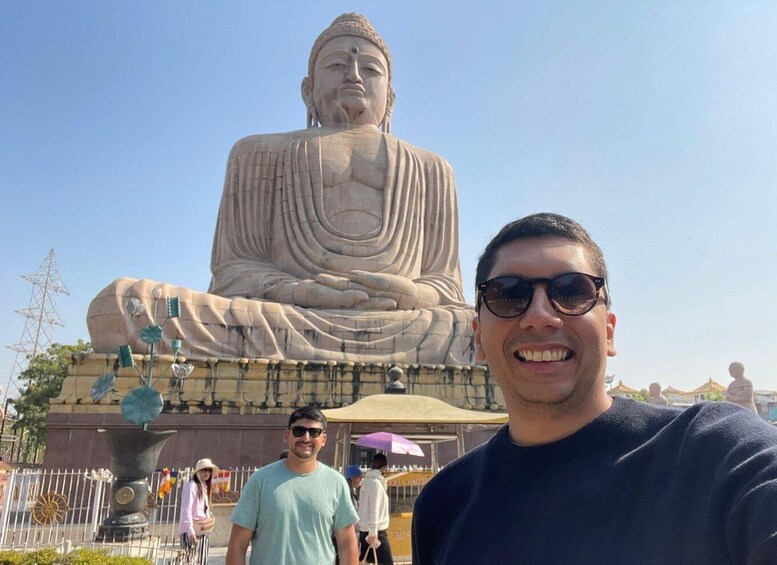 A large Buddha statue in a public square with a man in the foreground. 1