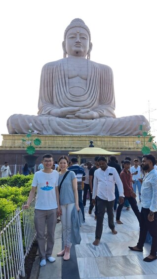 A large seated Buddha statue with a lotus base, surrounded by a crowd of people. 5
