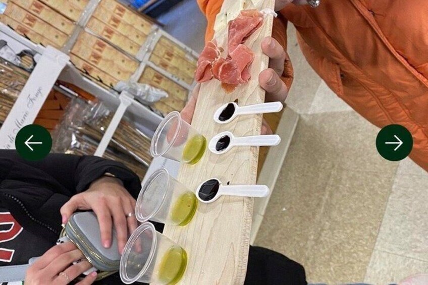 A person holding a wooden board with meat and several containers of sauces. 2