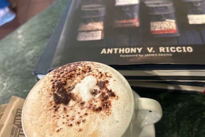 Une tasse de café surmontée d’une mousse onctueuse et saupoudrée de cacao, posée sur une table. 3