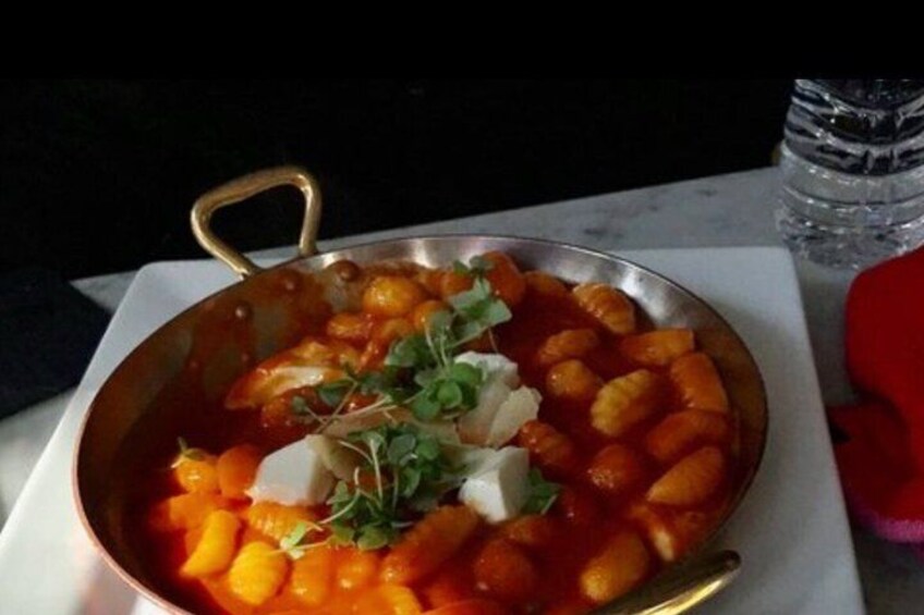 Una sartén de ñoquis con salsa de tomate, adornada con hierbas. 4