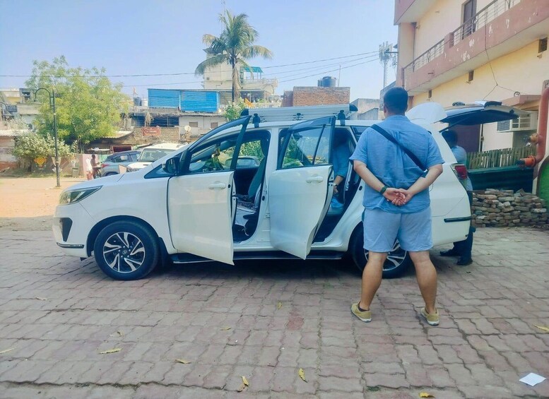 A white car parked on a paved area with its door open. 3