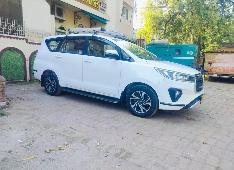 A white SUV parked on a paved area with a building in the background. 2