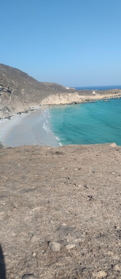 A rocky beach with clear turquoise waters and a distant view of the sea. 2