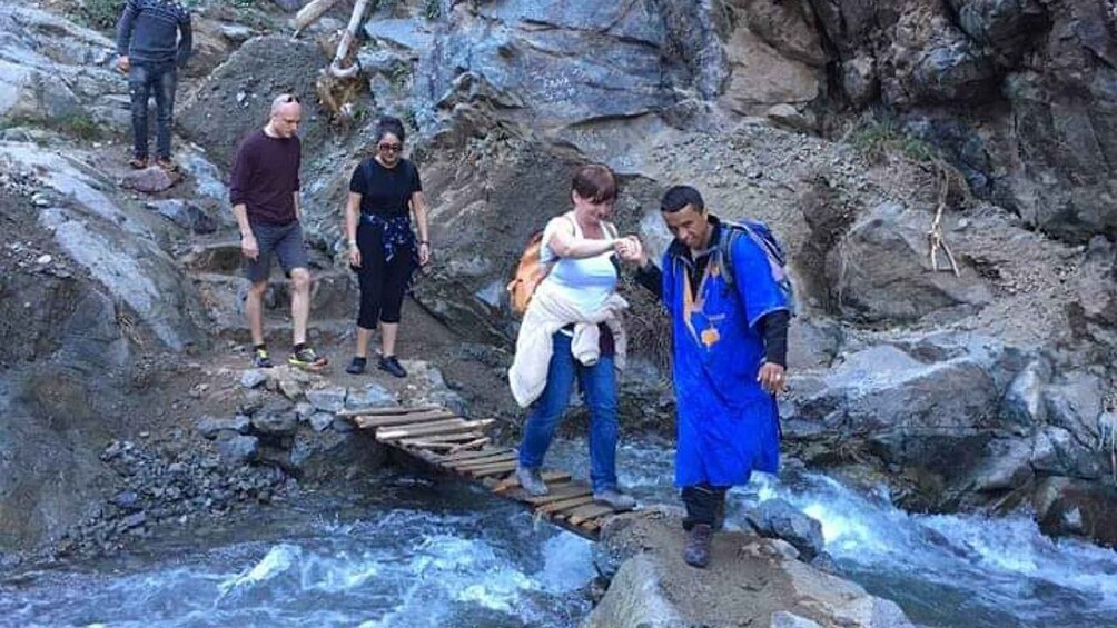People crossing a rocky stream on a wooden bridge. 5