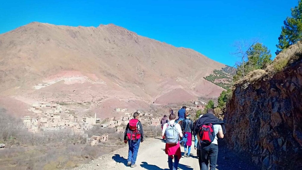 A group of hikers on a mountain trail with a village in the valley below. 3