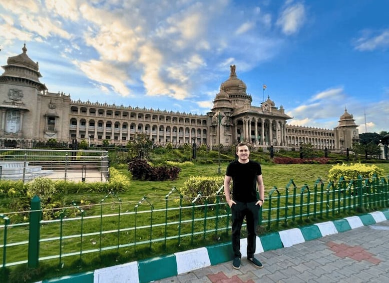 A person standing in front of a large, historic building with domed structures and a long facade. 4