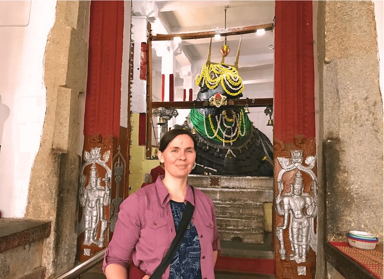 A person standing in front of a temple entrance with a deity statue. 2