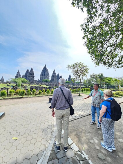 A group of people standing on a paved area with a temple complex in the background. 4