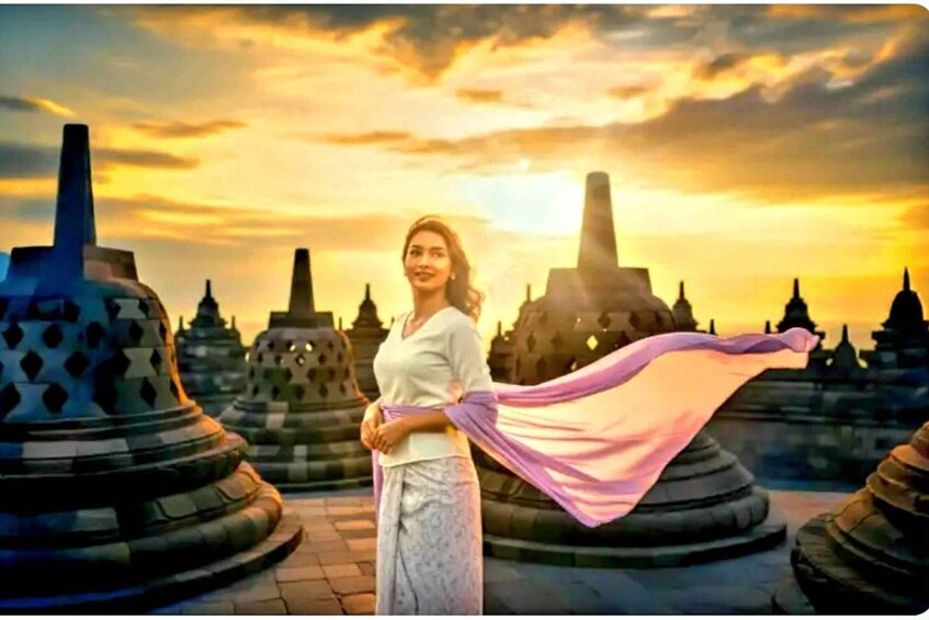 A person standing in front of temple structures with a sunset in the background. 1