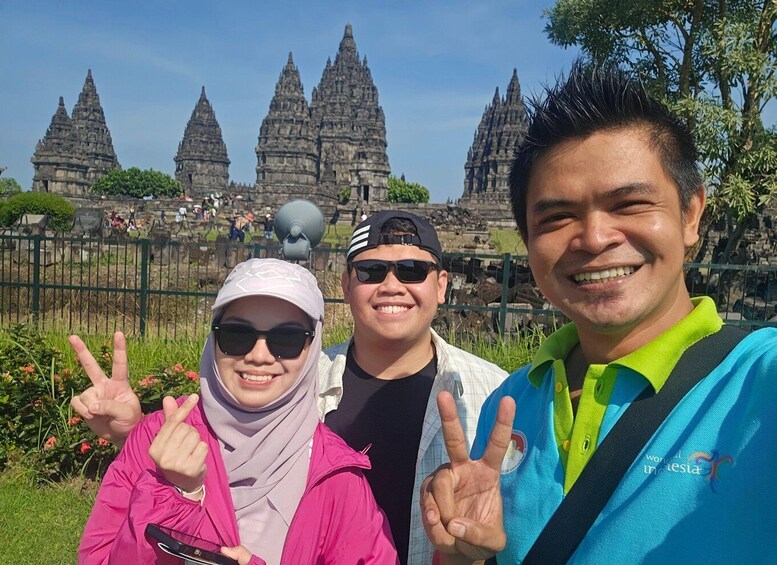 Three people posing in front of ancient temple ruins with multiple spires. 3