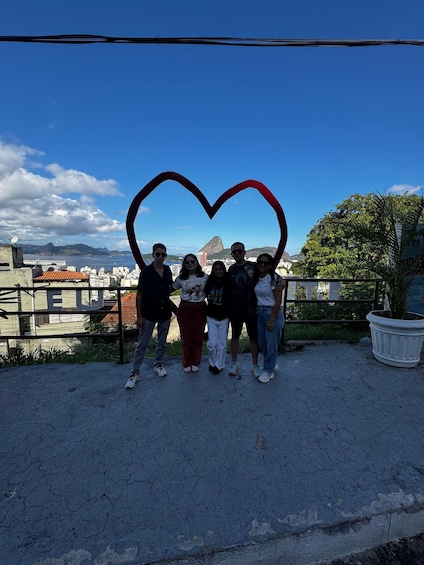 A group of people standing in front of a heart-shaped structure with a cityscape and mountains in the background. 3