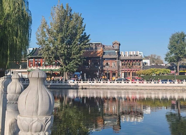 A traditional Chinese courtyard with stone lion statues, a reflection of buildings, and a clear blue sky. 1