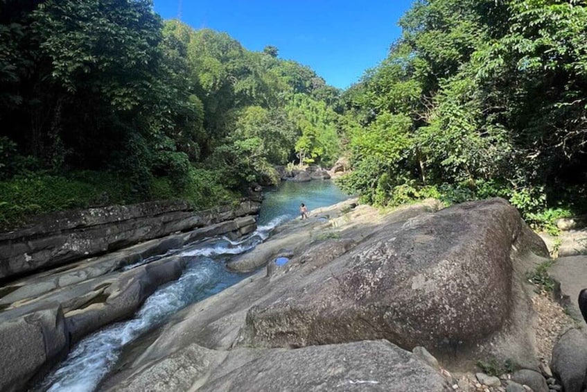 A river flowing through a forested area with large rocks in the foreground. 3